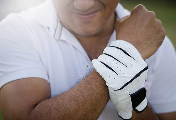A golfer wincing and holding his wrist